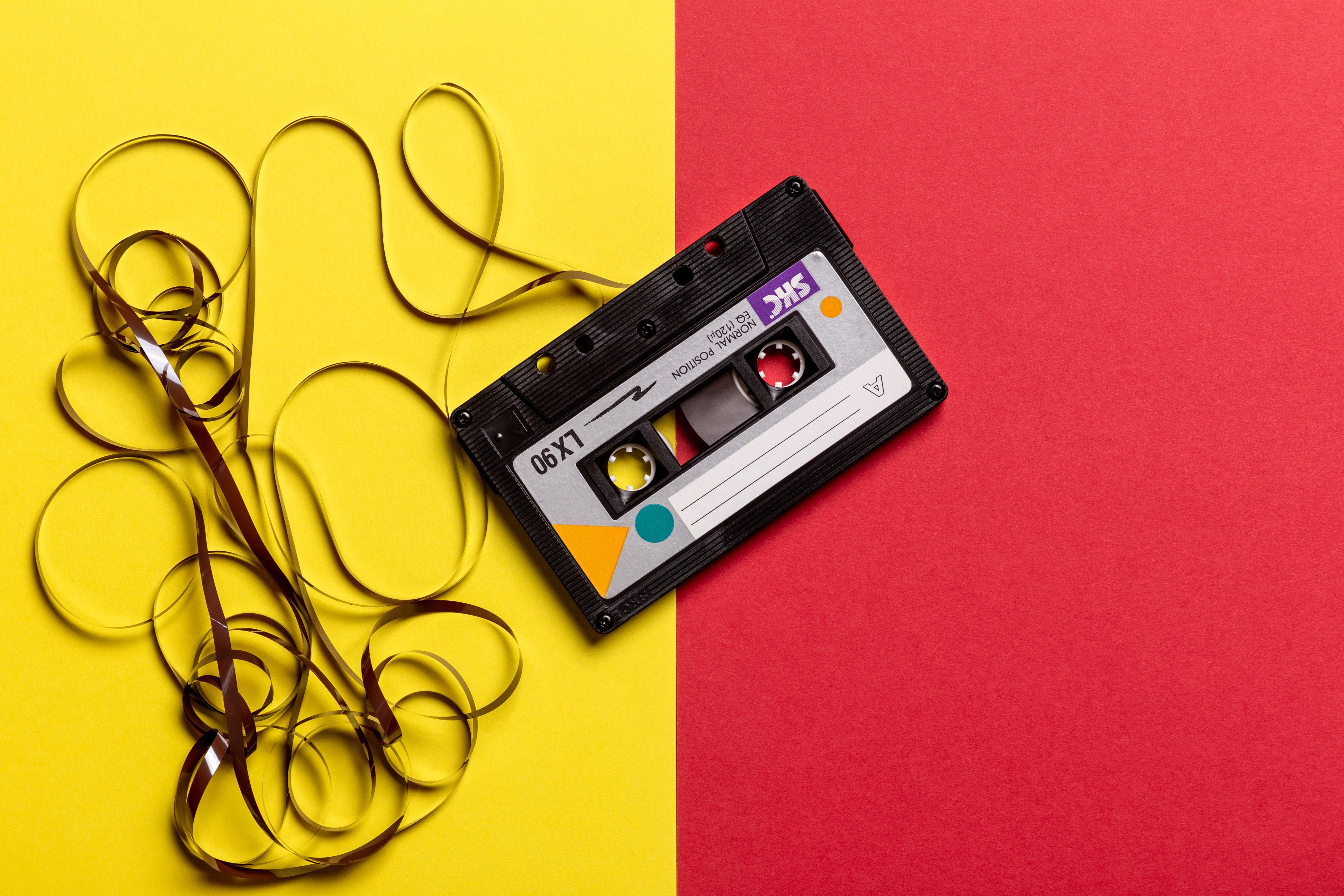 Black cassette tape on top of red and yellow surface 1626481